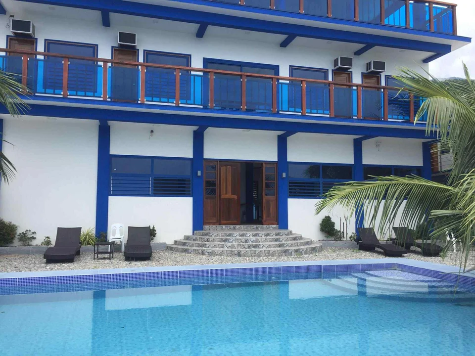 Blue-and-white resort facade, balconies, and swimming pool