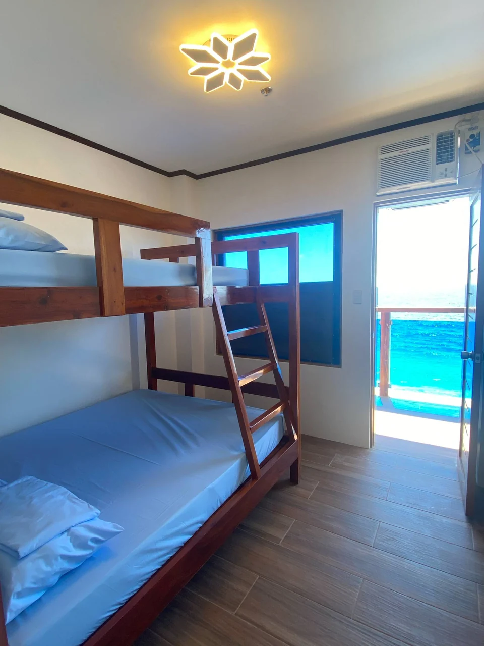 Wooden bunk bed inside a resort room with an open door facing the sea